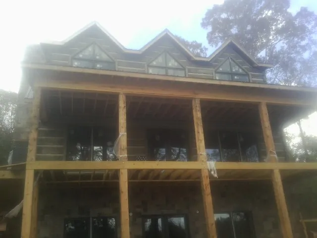 Dormers and porch framing on a large log home under construction — Roof Coating work by our crew in Ridgeway